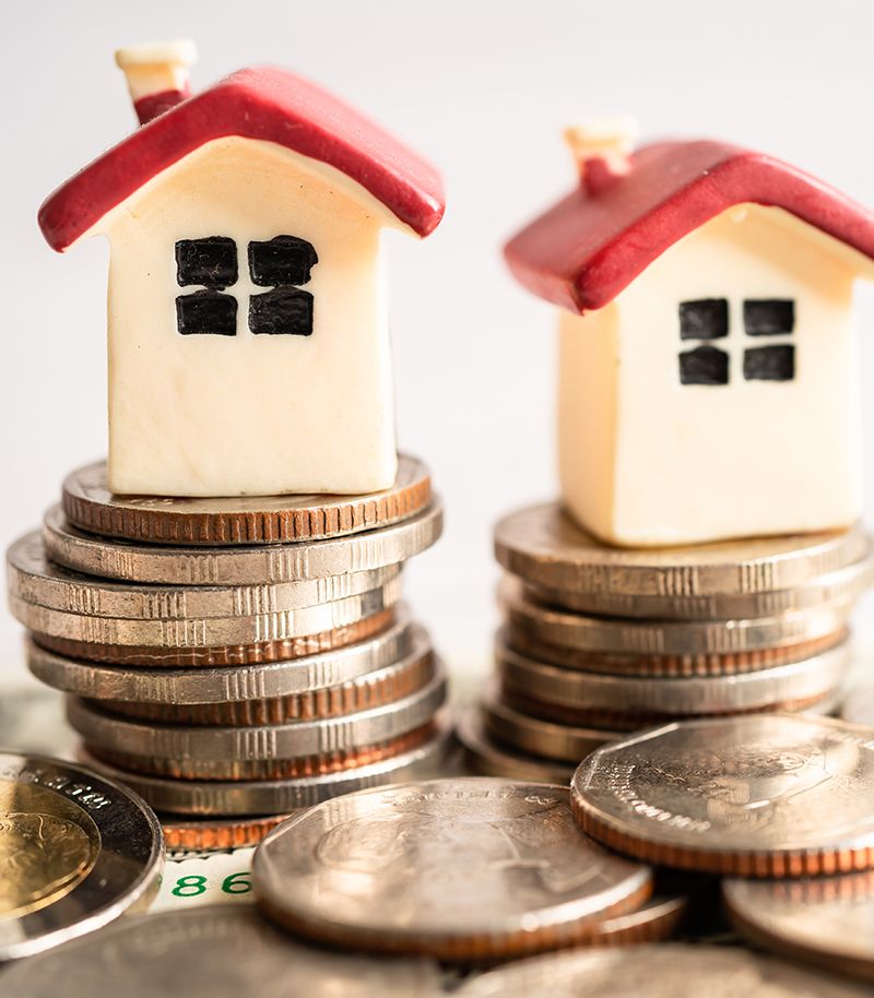 Monedas apiladas con unas figuras de casitas encima. Imagen que hace referencia a arrendamientos y desahucios.