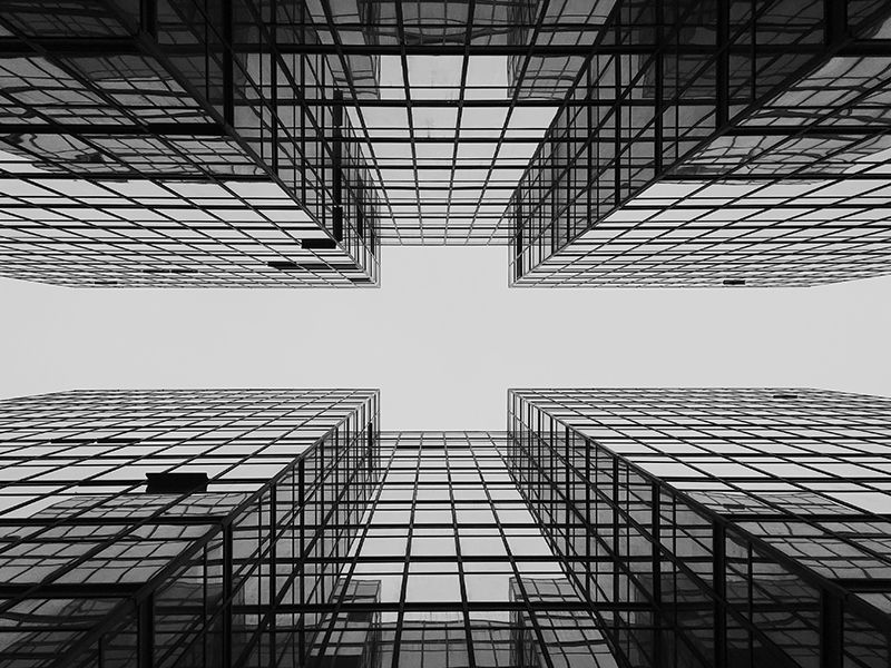 Foto en blanco y negro de una vista desde abajo de un bloque de unos grandes edificios. Imagen que hace referencia a la administración de fincas.